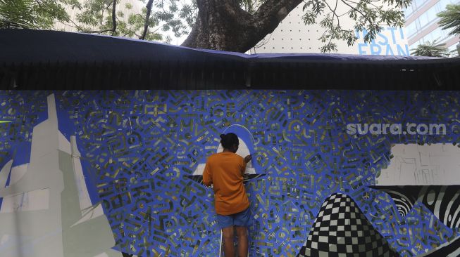 Seniman membuat seni mural berisi "Kampanye Bersihkan Udara di Banyak Kota di Seluruh Dunia" di depan Institut Prancis Indonesia (IFI), Jakarta, Rabu (2/12/2020). [Suara.com/Angga Budhiyanto]