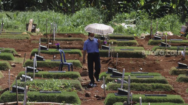 Warga berziarah ke makam keluarganya yang meninggal akibat COVID-19 di TPU Pondok Ranggon, Jakarta, Rabu (2/12/2020). [Suara.com/Angga Budhiyanto]