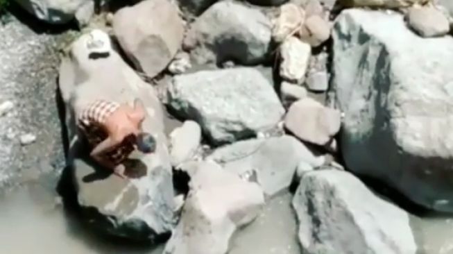 Viral! Seorang Kakek Salat di Atas Batu Bantaran Sungai di Pemalang