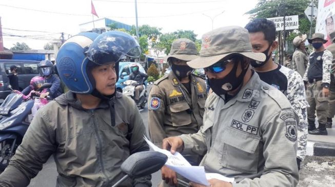 Salah seorang warga mengaku bernama Budi memprotes petugas Satpol PP dan menganggap tebang pilih dalam menertiblan APK paslon ilegal di Jalan Ciater Raya, Serpong, Kota Tangsel, Rabu (2/12/2020). [Suara.com/Wivy]