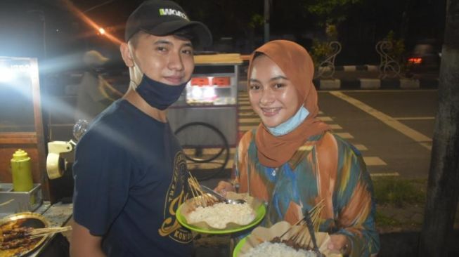 Sejoli penjual sate di Gresik, Nurul Amaliyah Ratih (19) dan Andi Yusuf Habibi (21), yang viral di Tiktok menunjukan sajian yang dihidangkan. [Suara.com/Amin Alamsyah]