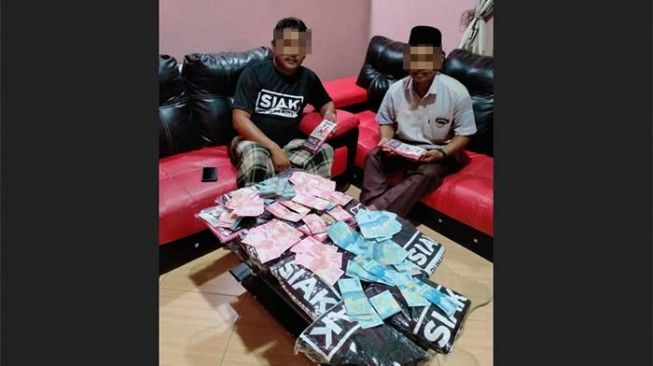 Foto warga memamerkan uang terkait Pilkada di Siak beredar di media sosial. [Tangkapan layar/WhatsApp]