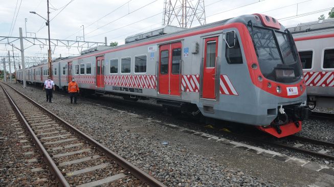 Petugas melintas didekat Kereta Rel Listrik (KRL) saat berada di Stasiun Klaten, Jawa Tengah, Jumat (4/12/2020). [ANTARA FOTO/Aloysius Jarot Nugroho]