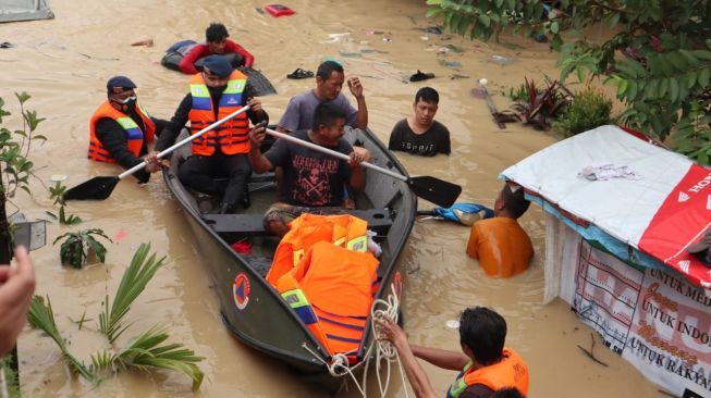 Personel Brimob Sumut melakukan evakuasi terhadap warga yang terdampak banjir. [Foto: Istimewa]