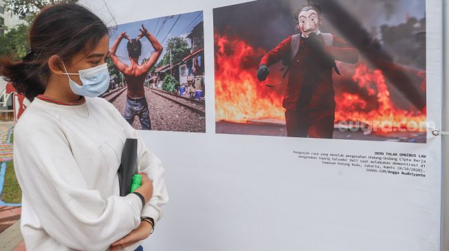 Seorang pengunjung mengamati karya dari pewarta foto suara.com yang ikut terpilih di pameran fotografi Rekam Jakarta 2020 di Thamrin 10, Jakarta Pusat, Sabtu (5/12). [Suara.com/Alfian Winanto]