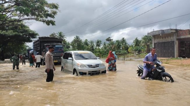 Warga melintasi banjir di Gampong Keude, Kecamatan Darul Aman Kabupaten Aceh Timur, Sabtu (5/12/2020). (ANTARA/Hayaturrahmah)