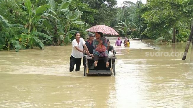 Warga dievakuasi menggunakan becak saat mengungsi di Jalan Raya Panimbang-Munjul, Pandeglang, Banten, Senin (7/12/2020). [Suara.com/Saepulloh]