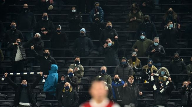 Suporter menggunakan masker saat menghadiri laga Tottenham Hotspur menghadapi Arsenal pada pertandingan pekan ke-11 Liga Inggris di Tottenham Hotspur Stadium, Minggu (6/12/2020). [Glyn KIRK / POOL / AFP]