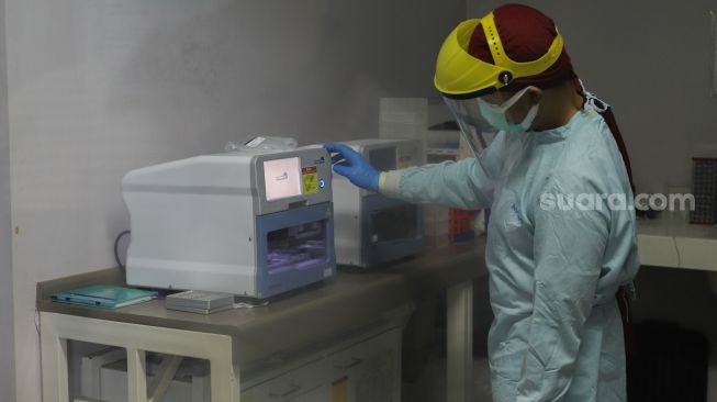 Petugas laboratorium memeriksa sampel hasil swab test Covid-19 di PRVKP FKUI, Jakarta, Senin (7/12/2020). [Suara.com/Alfian Winanto]