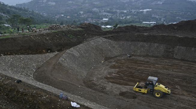 Pekerja dibantu alat berat menyelesaikan pembangunan tempat pemusnahan sampah modern (Sanitary Landfill) di TPA Pasir Bajing, Banyuresmi, Kabupaten Garut, Jawa Barat, Senin (7/12/2020). [ANTARA FOTO/Candra Yanuarsyah]