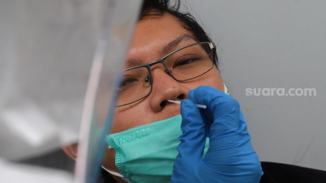 Petugas melakukan pengambilan sampel swab test Covid-19 di PRVKP FKUI, Jakarta, Senin (7/12). [Suara.com/Alfian Winanto]