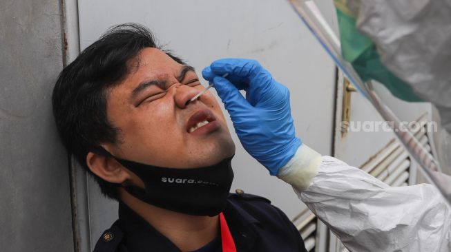 Petugas melakukan pengambilan sampel lendir sebagai bagian dari pemeriksaan swab Covid-19 di PRVKP FKUI, Jakarta, Senin (7/12/2020). [Suara.com/Alfian Winanto]