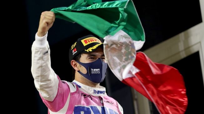 Pembalap tim Racing Point Sergio Perez mengibarkan bendera negaranya, Meksiko, usai meraih podium kemenangan perdana di Formula 1 tepatnya di F1 GP Sakhir di Sikruit Internasional Bahrain, Senin (7/12/2020) dini hari WIB. [KAMRAN JEBREILI / POOL / AFP]