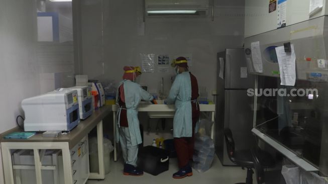 Petugas laboratorium memeriksa sampel hasil swab test Covid-19 di PRVKP FKUI, Jakarta, Senin (7/12/2020). [Suara.com/Alfian Winanto]