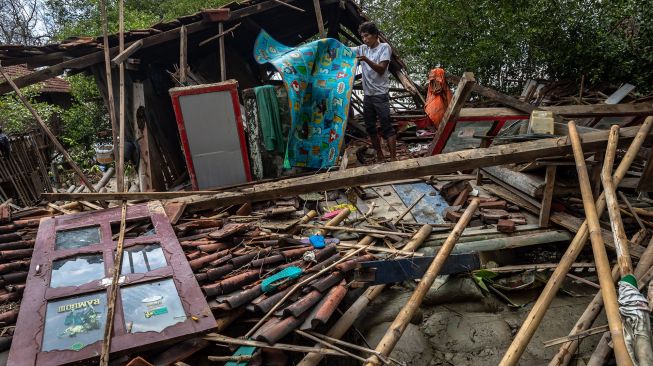 Seorang warga menyelamatkan harta benda di rumahnya yang roboh akibat diterjang ombak di Desa Bedono, Sayung, Demak, Jawa Tengah, Selasa (8/12/2020).  [ANTARA FOTO/Aji Styawan]