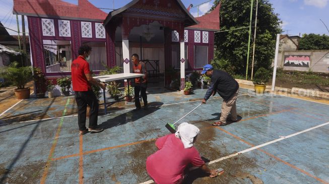 Petugas dibantu warga mempersiapkan Tempat Pemungutan Suara (TPS) dengan nuansa adat Padang di Kampung Benda Barat, Kelurahan Cipayung, Kota Depok, Jawa Barat, Selasa (8/12/2020). [Suara.com/Angga Budhiyanto]