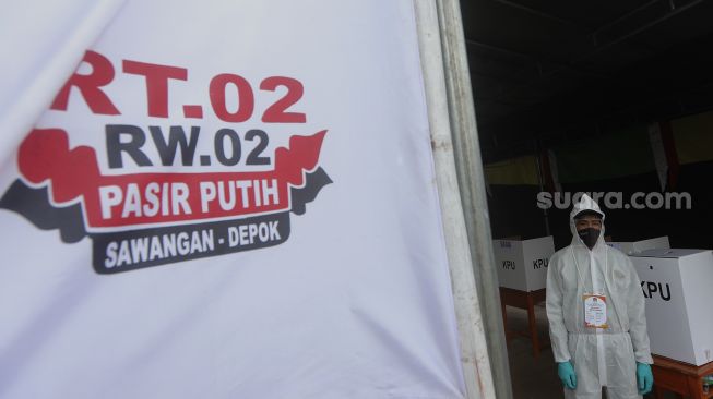 Petugas KPPS mengenakan pakaian hazmat dan Alat Perlindungan Diri (APD) di Tempat Pemungutan Suara (TPS) 13 pada Pilkada Kota Depok 2020 di Pasir Putih, Sawangan, Depok, Jawa Barat, Rabu (9/12/2020). [Suara.com/Angga Budhiyanto]