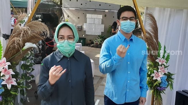 Wali Kota Tangerang Selatan Airin Rachmi Diany (kiri) bersama putranya Ghifari Al Chusaeri Wardana usai menggunakan hak pilihnya dalam Pilkada Tangsel 2020 di TPS 24 Sutera Narada, Pakulonan, Serpong Utara, Rabu (9/12/2020). [Suara.com/Wivy]