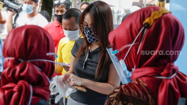 Pedangdut Ayu Ting Ting mengenakan sarung tangan saat akan melakukan pemilihan kepala daerah di TPS 06 Sukmajaya, Depok, Jawa Barat, Rabu (9/12). [Suara.com/Alfian Winanto]