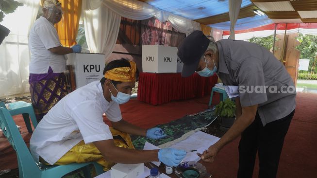 Petugas Kelompok Penyelenggara Pemungutan Suara (KPPS) meneteskan tinta kepada warga usai menggunakan hak pilihnya di TPS 33, Kampung Benda Barat, Kelurahan Cipayung, Kota Depok, Jawa Barat, Rabu (9/12/2020). [Suara.com/Angga Budhiyanto]