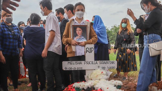 Saudara kembar Melisha, Melitha Sidabutar difoto diatas pusara Penyanyi Melisha Priscilla Sidabutar atau Melisha Idol di TPU Padurenan, Bekasi, Jawa Barat, Kamis (10/12). [Suara.com/Alfian Winanto] 