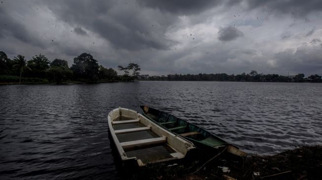 Perahu bersandar dengan latar belakang awan hitam di kawasan Setu Cikaret, Kabupaten Bogor, Jawa Barat, Kamis (10/12/2020). [ANTARA FOTO/Yulius Satria Wijaya]