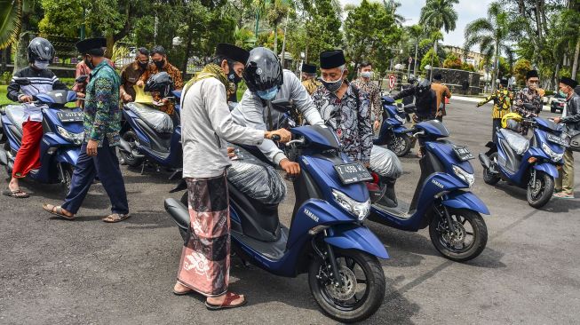 Pengurus Majelis Ulama Indonesia (MUI) memeriksa kendaraannya saat penyerahan bantuan hibah kendaraan di Halaman Pendopo, Kabupaten Ciamis, Jawa Barat, Kamis (10/12/2020).  [ ANTARA FOTO/Adeng Bustomi]