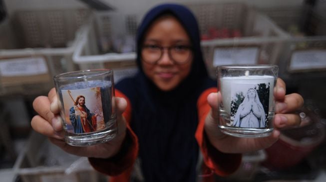 Seorang anak menunjukan hasil produksi lilin yang telah jadi saat membantu orang tuanya, di Candi, Ampel, Boyolali, Jawa Tengah, Jumat (11/12/2020).  [ANTARA FOTO/Aloysius Jarot Nugroho]