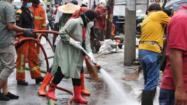 Wali Kota Surabaya Tri Rismaharini (tengah) membersihkan jalan saat kerja bakti pembersihan saluran air di Mulyosari, Surabaya, Jawa Timur, Sabtu (12/12/2020).  ANTARA FOTO/Didik Suhartono
