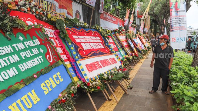 Warga melihat karangan bunga yang membanjiri halaman depan Polda Metro Jaya, Jakarta Selatan, (12/12). [Suara.com/Alfian Winanto]