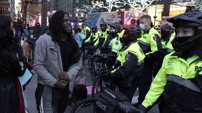 Seorang pengunjuk rasa berteriak pada petugas NYPD setelah sebuah mobil menabrak beberapa pengunjuk rasa Black Lives Matter pada 11 Desember 2020. [TIMOTHY A. CLARY / AFP]
