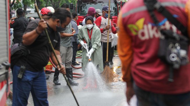 Wali Kota Surabaya Tri Rismaharini (tengah) membersihkan jalan saat kerja bakti pembersihan saluran air di Mulyosari, Surabaya, Jawa Timur, Sabtu (12/12/2020).  ANTARA FOTO/Didik Suhartono
