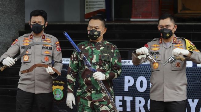 Pangdam Jaya Mayjen TNI Dudung Abdurachman (tengah) bersama Kapolda Metro Jaya Irjen Fadil Imran (kanan) dan Karopaminal Divpropam Polri Brigjen Hendra Kurniawan (kiri) menunjukkan barang bukti saat memberikan keterangan pers terkait kasus penyerangan anggota kepolisian di Polda Metro Jaya, Jakarta, Senin (7/12/2020). Kapolda Metro Jaya Irjen Pol Fadil Imran mengungkap telah terjadi penyerangan kepada sepuluh anggota kepolisian oleh pengikut Rizieq Shihab di ruas Tol Jakarta-Cikampek KM 50 pada Senin (7/12) dini hari. Dalam kejadian tersebut, anggota kepolisian terpaksa melakukan tindakan tegas dan terukur sehingga enam diantara pengikut Rizieq Shihab tewas ditembak. [Suara.com/Angga Budhiyanto]