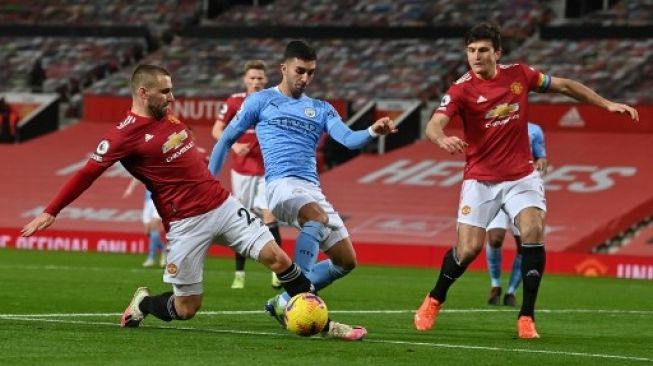 Pemain Manchester United Luke Shaw mencoba menghentikan laju pemain Manchester City Ferran Torres (tengah) dalam pertandingan Liga Premier Inggris yang berlangsung di Old Trafford, Minggu (13/12/2020). [AFP]