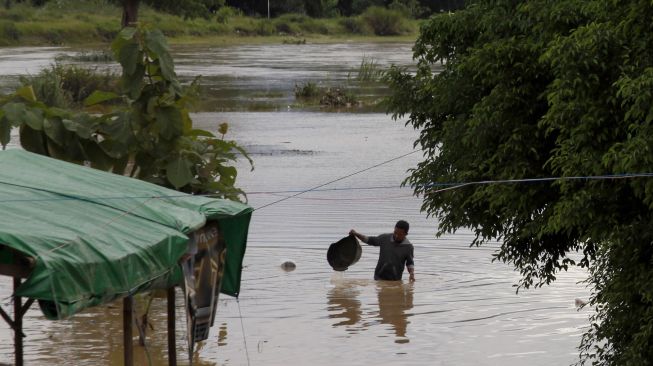 Warga berjalan melintasi banjir yang menggenangi permukiman di Kampung Sewu, Jebres, Solo, Jawa Tengah, Senin (14/12/2020).  ANTARA FOTO/Maulana Surya