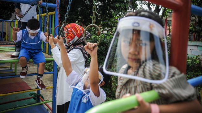 Seorang guru mengawasi murid yang bermain saat simulasi pembukaan dan pembelajaran tatap muka Taman Kanak-kanak (TK) dengan protokol kesehatan di TK Negeri Pembina Cimahi, Jawa Barat, Senin (14/12/2020).  [ANTARA FOTO/Raisan Al Farisi]