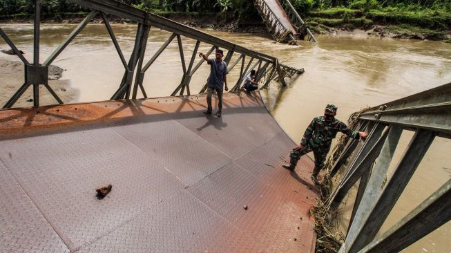 Warga bersama anggota TNI Koramil 27 Geureudong Pase melihat kondisi jembatan penghubung yang putus di Desa Darussalam, Kecamatan Geureudong Pase, Aceh Utara, Aceh, Minggu (13/12/2020). [ANTARA FOTO/Rahmad]