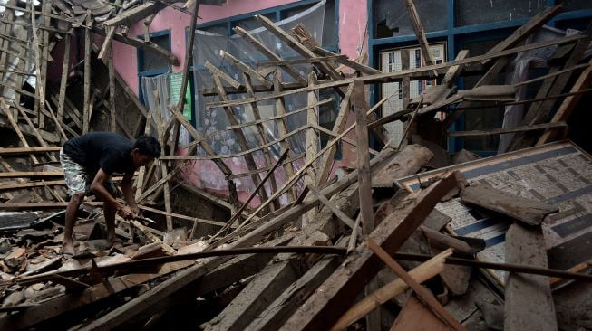 Warga membereskan puing-puing bangunan di SDN Bakakan Loa 2, Pangatikan, Kabupaten Garut, Jawa Barat, Selasa (15/12/2020).  [ANTARA FOTO/Candra Yanuarsyah]