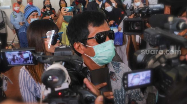 Komedia Kiwil bersama dengan istri mudanya, Eva Bellissima mencoba menghindari awak media saat tiba di Terminal 2 Bandara Soekarno Hatta, Tangerang, Banten, Rabu (16/12). [Suara.com/Alfian Winanto]