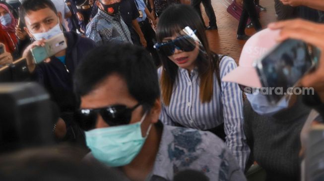 Komedian Kiwil bersama dengan istri mudanya, Eva Bellissima mencoba menghindari awak media saat tiba di Terminal 2 Bandara Soekarno Hatta, Tangerang, Banten, Rabu (16/12). [Suara.com/Alfian Winanto]