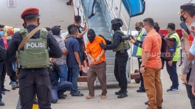 Tersangka teroris jaringan Jamaah Islamiyah (JI) Lampung tiba di Bandara Soetta, Tangerang, setelah ditangkap Tim Densus 88 Mabes Polri, Rabu (16/12/2020). [Suara.com/Hairul Alwan]