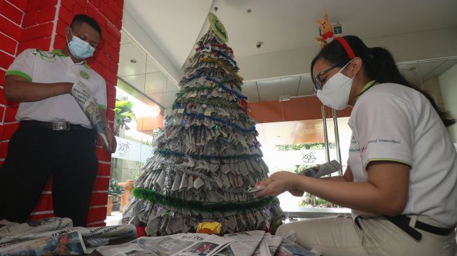 Pekerja menggulung kertas koran bekas sebagai bahan untuk membuat pohon Natal di Hotel Zest, Surabaya, Jawa Timur, Kamis (17/12/2020). [ANTARA FOTO/Didik Suhartono]