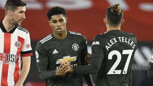 Penyerang Manchester United Marcus Rashford (tengah) merayakan gol bersama rekan satu timnya setelah merobek gawang Sheffiled United dalam laga pekan ke-13 Liga Inggris di stadion Bramall Lane, Jumat (18/12/2020) dini hari WIB. [PETER POWELL / POOL / AFP]