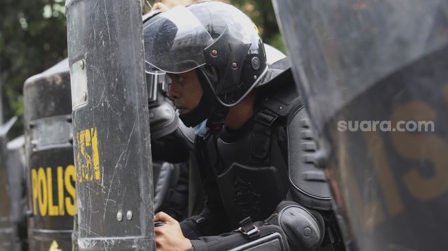 Aparat kepolisian melakukan penjagaan saat membubarkan paksa massa aksi 1812 yang akan menggelar aksi unjuk rasa di Jalan Abdul Muis, Jakarta, Jumat (18/12/2020). [Suara.com/Angga Budhiyanto]