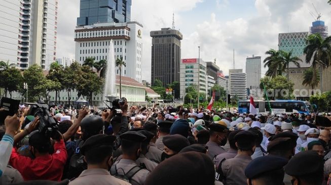 Sejumlah massa aksi 1812 di area sekitar Patung Kuda Arjuna Wijaya, Jalan Medan Merdeka Barat, Jakarta Pusat, Jumat (18/12/2020) langsung mendapat pengusiran dari aparat kepolisian. (Suara.com/Bagaskara)