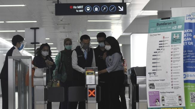 Petugas membantu penumpang melewati pintu tiket usai menaiki kereta MRT di Stasiun MRT Bundaran HI, Jakarta, Jumat (18/12/2020). [ANTARA FOTO/Indrianto Eko Suwarso]