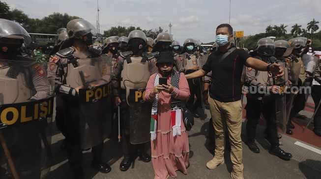 Aparat kepolisian membubarkan paksa massa aksi 1812 yang akan menggelar aksi unjuk rasa di kawasan Patung Kuda Arjuna Wiwaha, Jakarta, Jumat (18/12/2020). [Suara.com/Angga Budhiyanto]