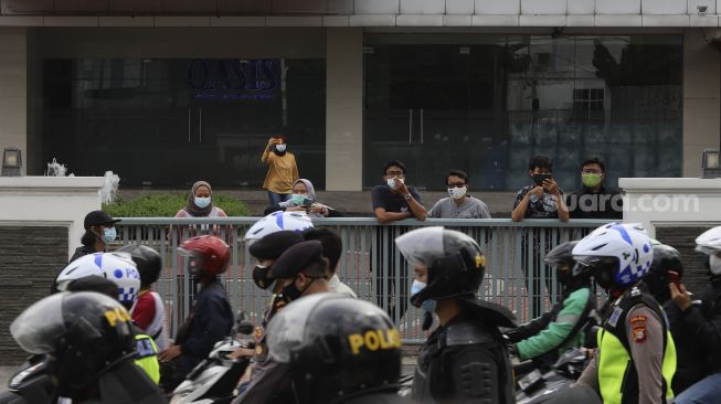 Sejumlah warga mengambil gambar saat aparat kepolisian membubarkan paksa massa aksi 1812 yang akan menggelar aksi unjuk rasa di Jalan Jati Baru, Jakarta, Jumat (18/12/2020). [Suara.com/Angga Budhiyanto]