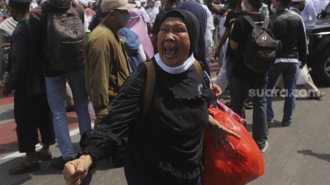 Ekspresi salah seorang massa aksi saat aparat kepolisian membubarkan paksa massa aksi 1812 yang akan menggelar aksi unjuk rasa di kawasan Patung Kuda Arjuna Wiwaha, Jakarta, Jumat (18/12/2020). [Suara.com/Angga Budhiyanto]