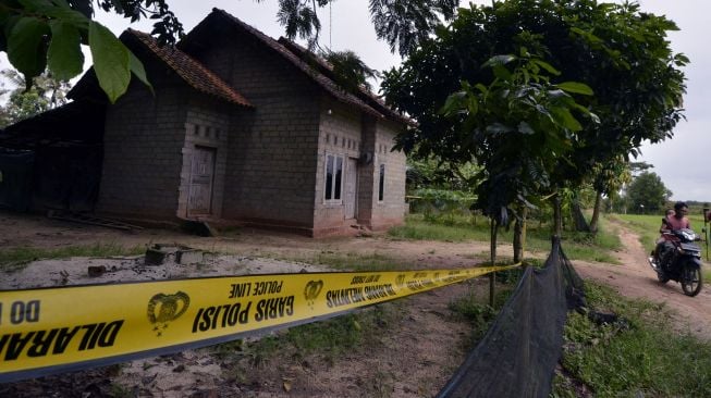 Warga melintasi rumah terduga teroris Taufik Bulaga alias Upik Lawanga di Desa Sribawono, Lampung Tengah, Lampung (19/12/2020). [ANTARA FOTO/Ardiansyah]